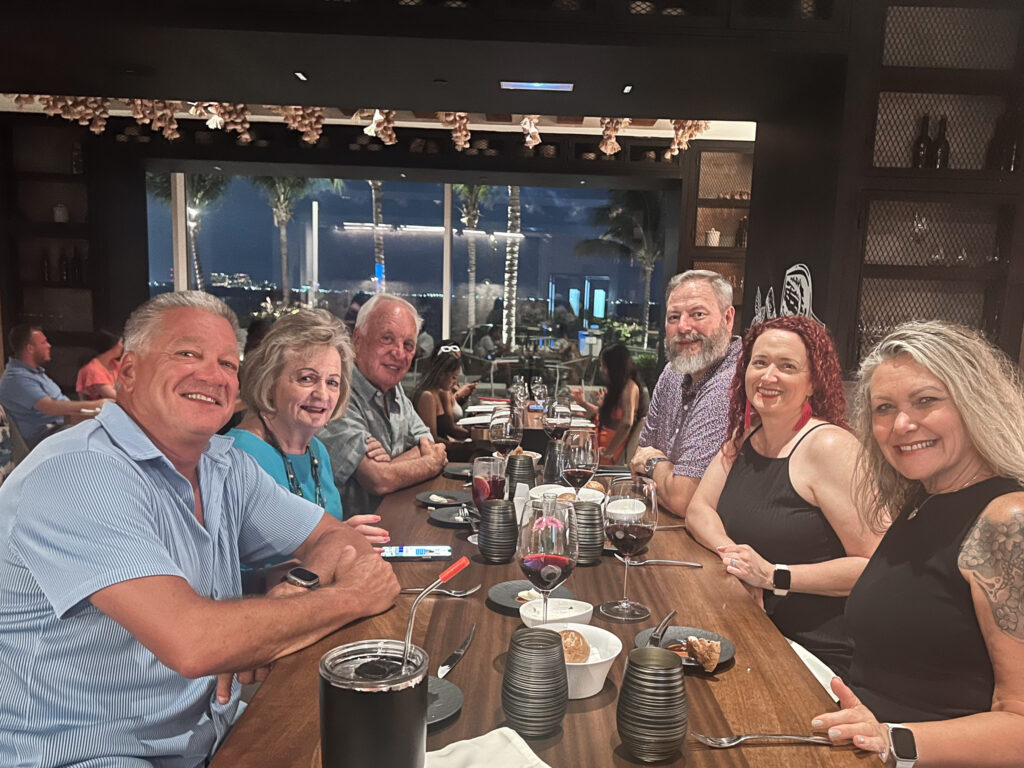 Rockwall travel agents and spouses sitting at table in restaurant smiling at camera